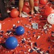 An image of a red carpeted floor covered in red, white, and blue confetti and balloons.