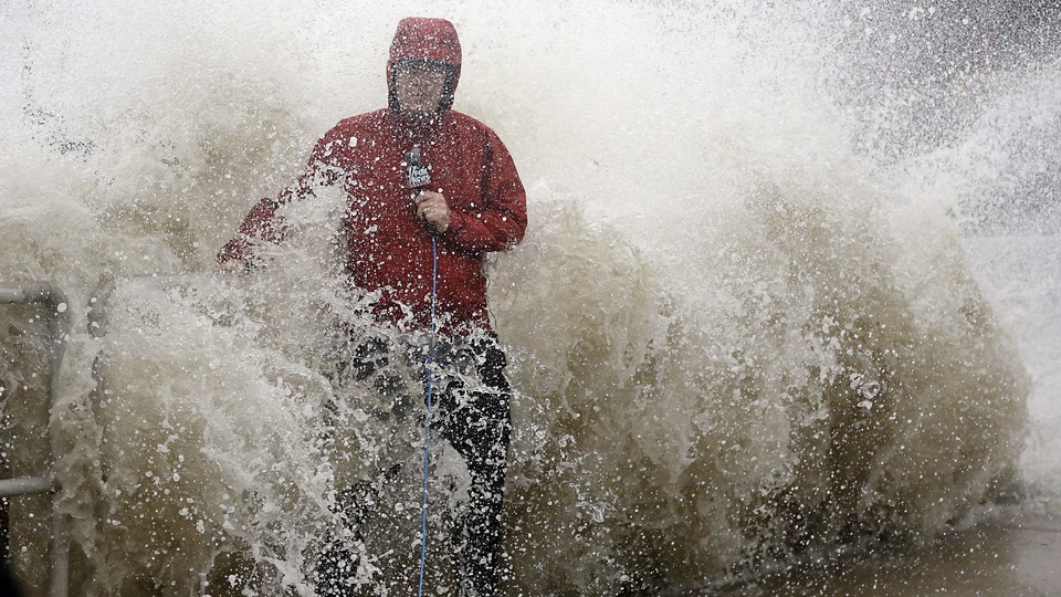 A news reporter doing a stand up near a sea wall in Cedar Key, Fla., is covered by an unexpected wave as Hurricane Hermine nears the Florida coast, Thursday, Sept. 1, 2016.