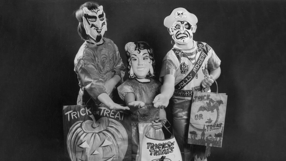 Three children in costumes holding out their hands for treats