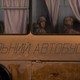 Two soldiers look out the window of a school bus.