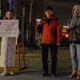 Three people hold up signs on placards and their mobile phones