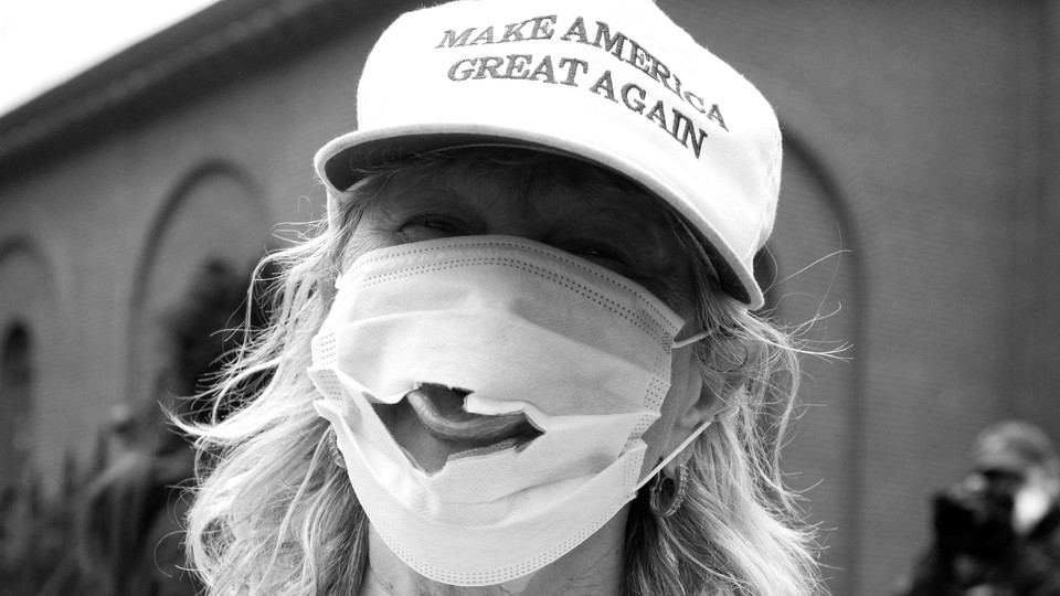 A woman wearing a Make America Great Again hat and a mask with a hole.