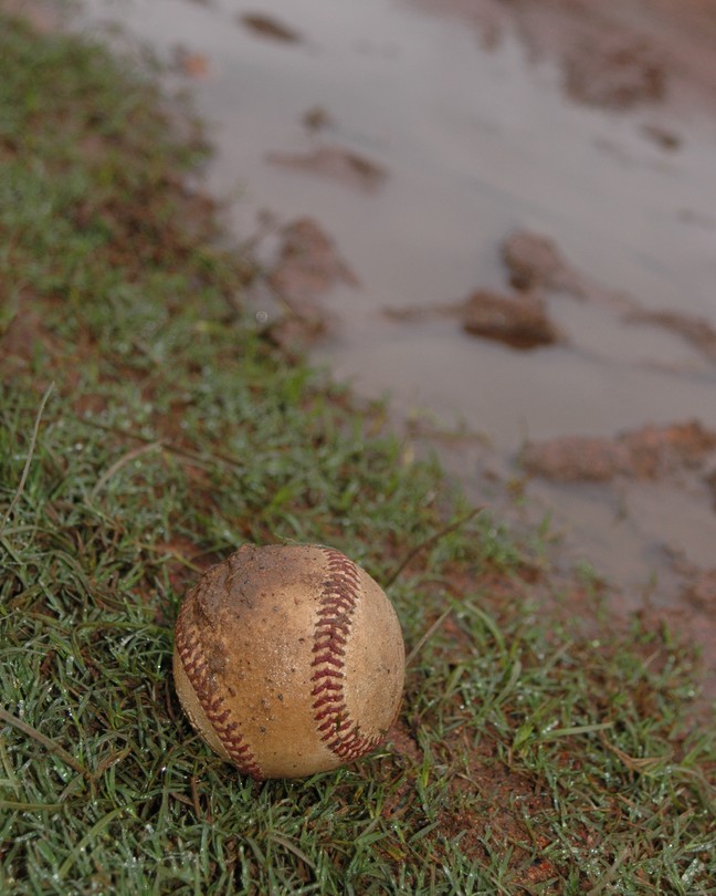 A baseball in a muddy field