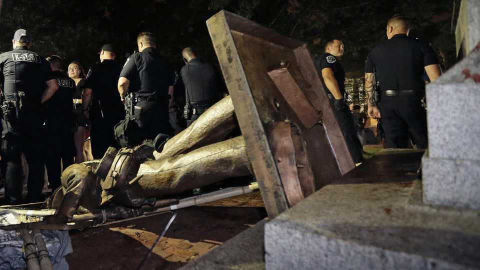 On Monday, August 20, 2018, police stand guard after the Confederate statue known as Silent Sam was toppled by protesters on campus at the University of North Carolina in Chapel Hill, North Carolina.