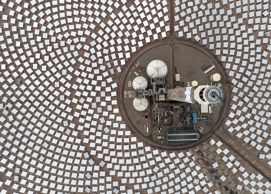 An aerial view of a solar tower surrounded by a broad array of reflecting mirrors