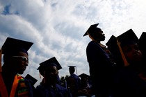 People in graduation caps sit together.