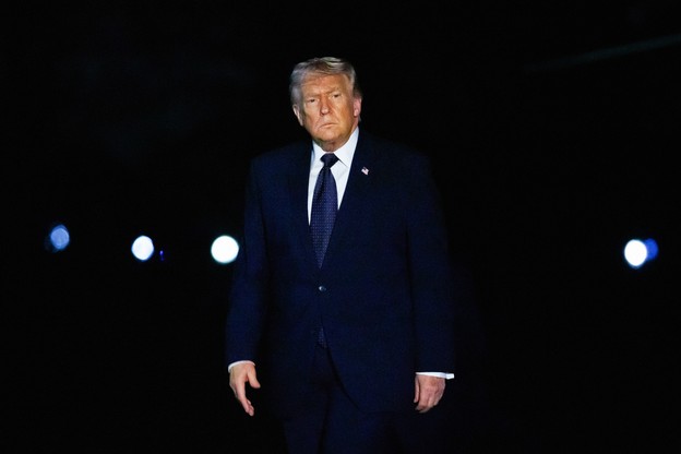 A photograph of Trump in a blue suit against a dark background