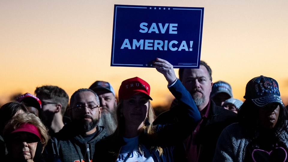 Supporters of Donald Trump hold up a sign at a "Save America" rally.