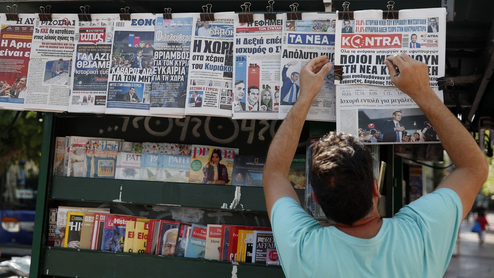 A vendor adjusts the front pages of the Greek newspapers, which refer to the election result