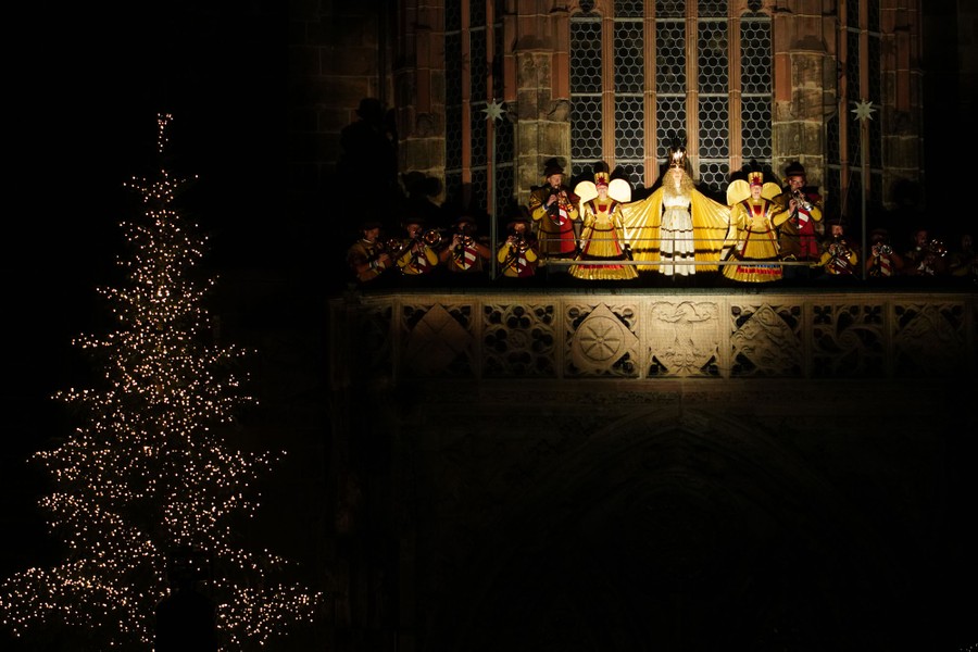 A spotlight shines on an exterior balcony of a church, showing several costumed performers.