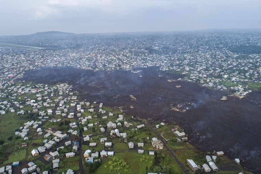 A wide strip of dark volcanic rock protrudes into a neighborhood, seen from above.
