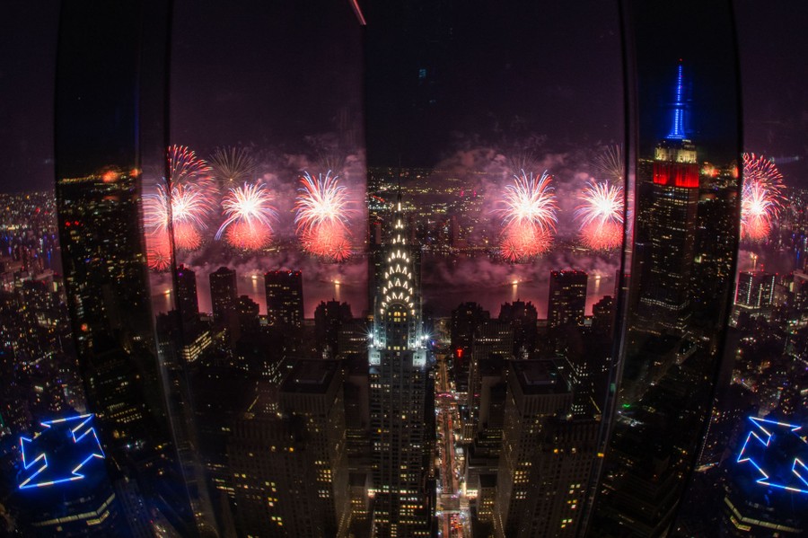 A view of fireworks in New York City, captured from a high observation deck.