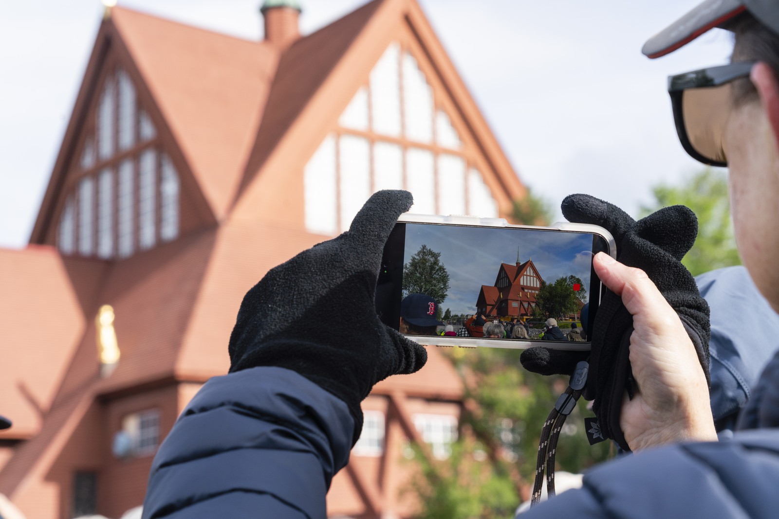 A person takes a photograph of a wooden church with their phone.