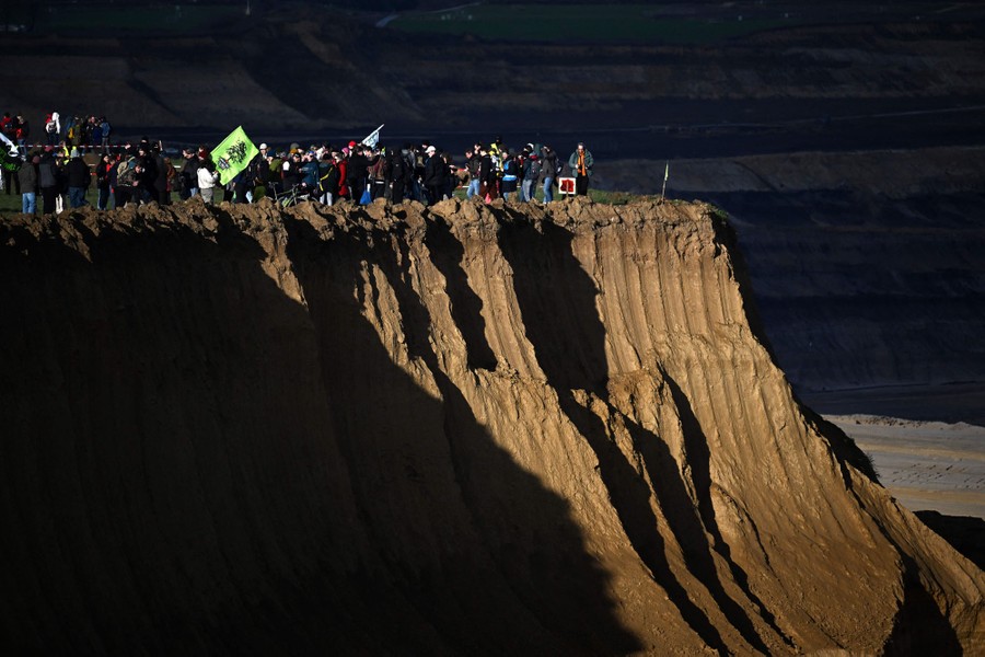 Protesters stand at the edge of a deep open coal-mine pit.
