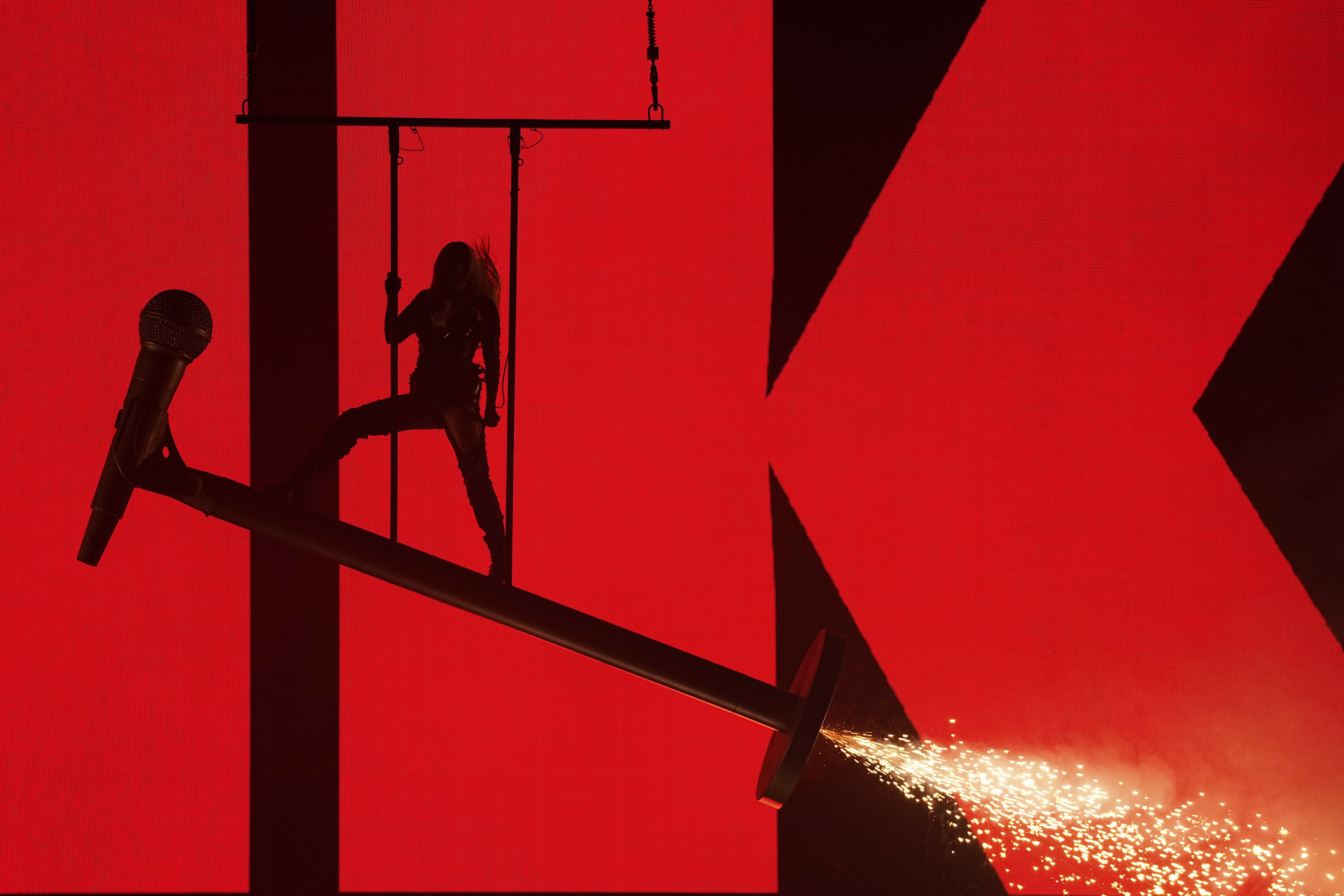 A singer hangs from the ceiling and stands on huge microphone props during the show.