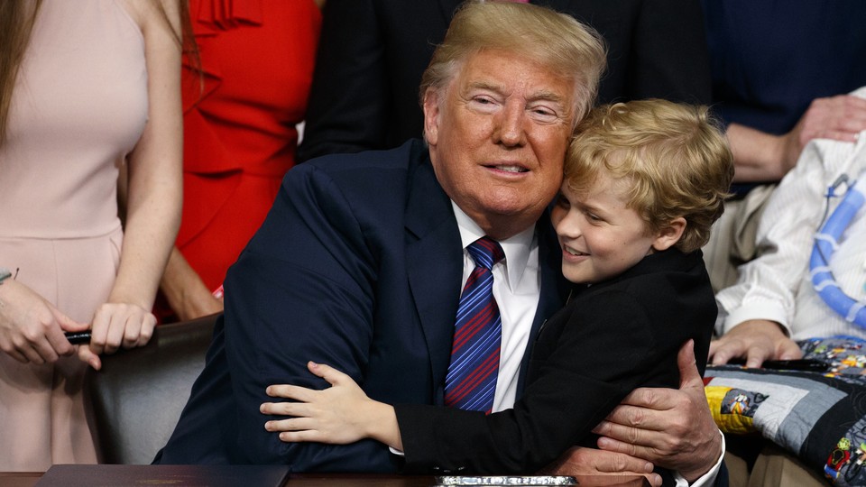 President Trump poses for a photo with Jordan McLinn, a child who has muscular dystrophy, in the Oval Office.