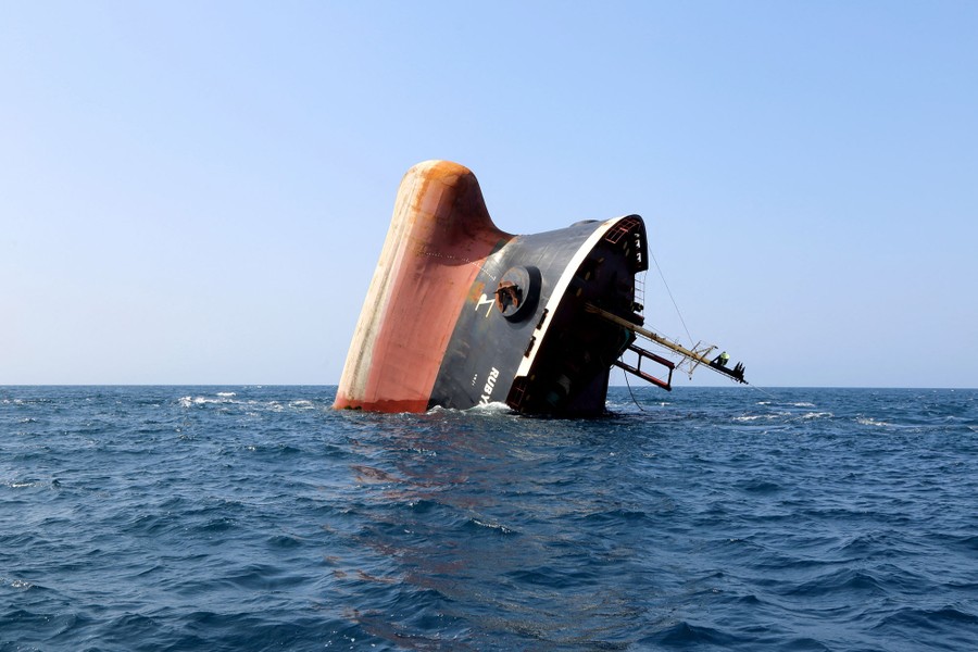 The bow of a partially sunk cargo ship pokes out of the ocean.