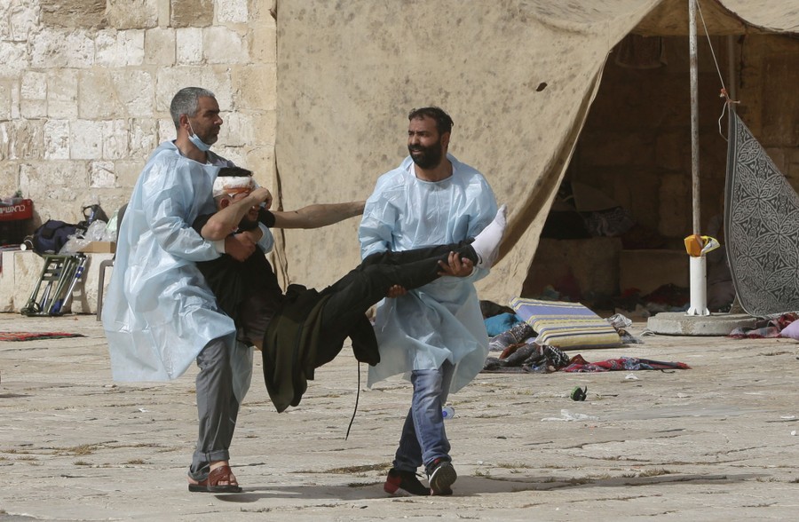 Two men carry a wounded protester.