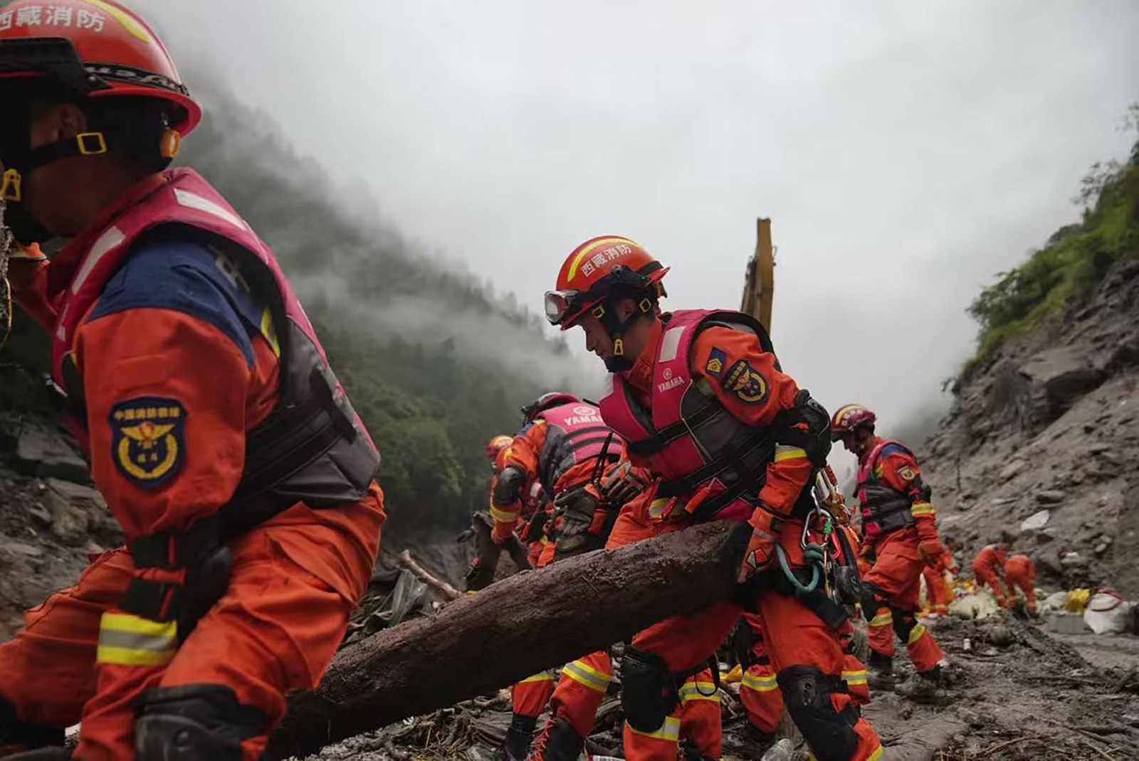 Rescue workers remove flood debris in a mountain valley.
