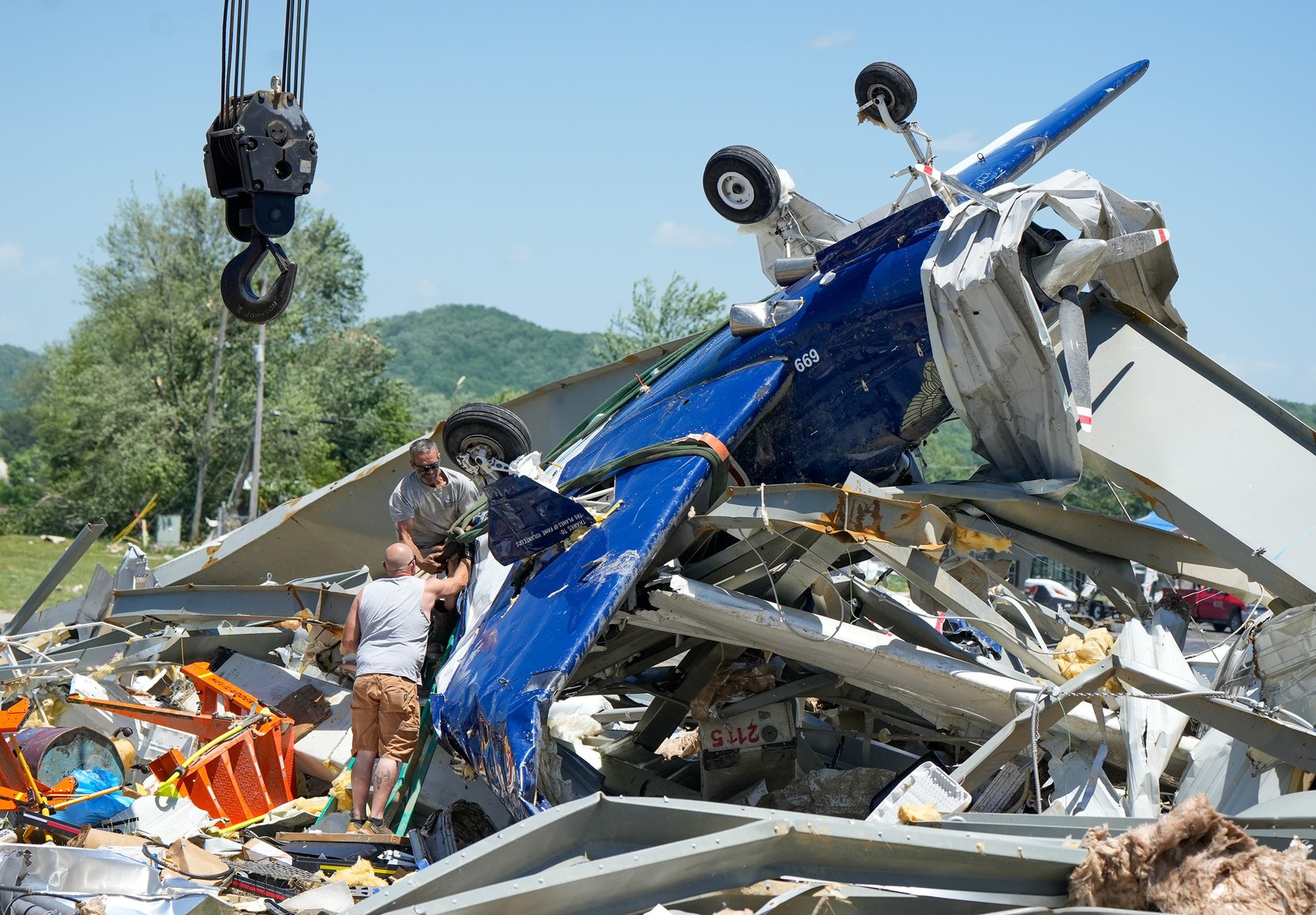 A small airplane is pulled from the rubble of a destroyed hangar.