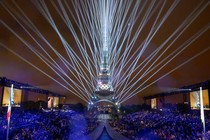 Lasers light up the sky around the Eiffel Tower, watched by a crowd at the Olympics opening ceremony.