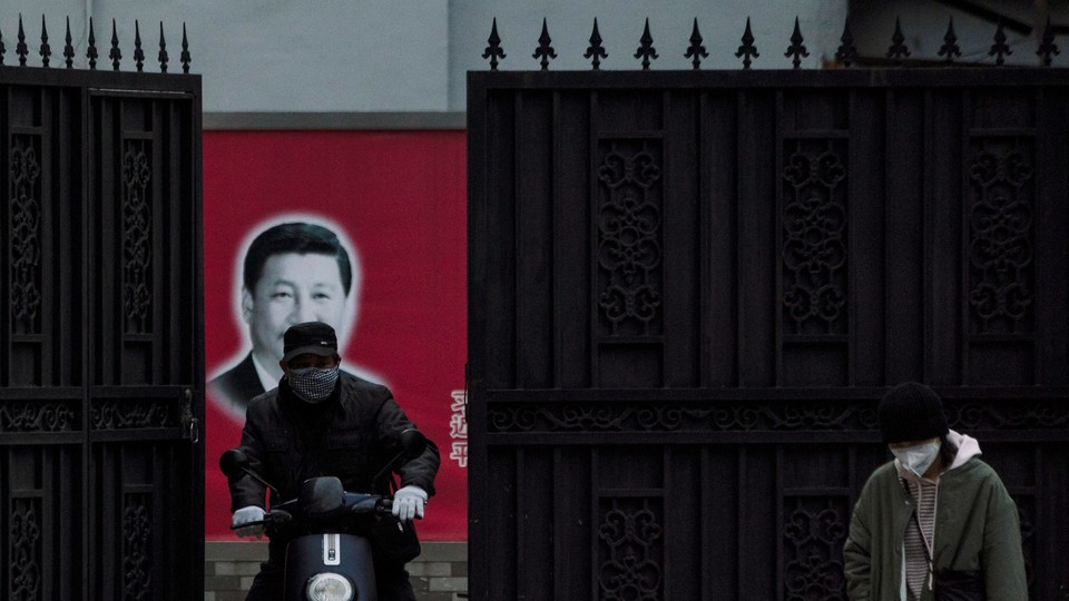 A masked man on a scooter in front of a portrait of Xi Jinping