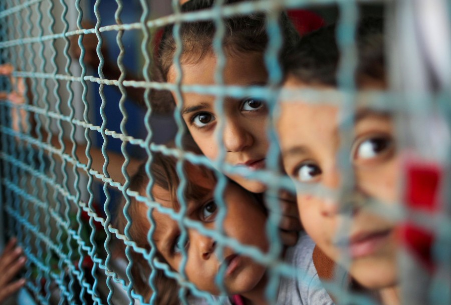 Several children look out of a screened window.