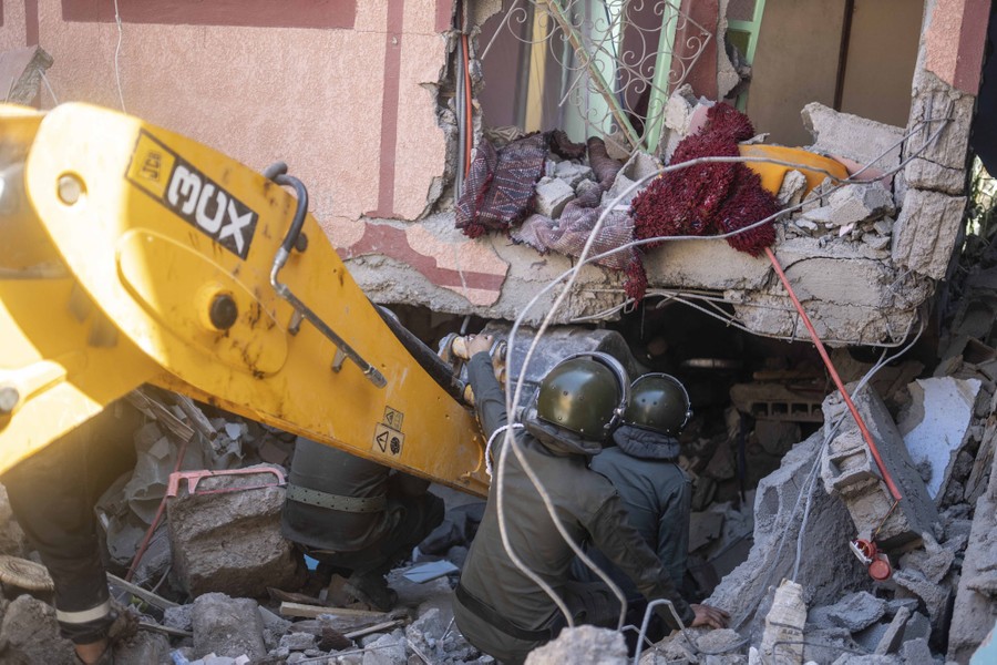 Workers maneuver beside construction equipment to rescue people from a quake-damaged building.
