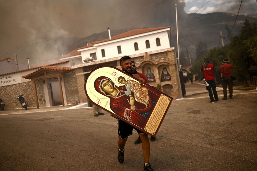 A person carries an icon of the Virgin Mary from a burning monastery.