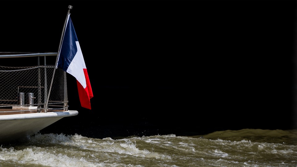 A boat flying a French flag navigates the Seine