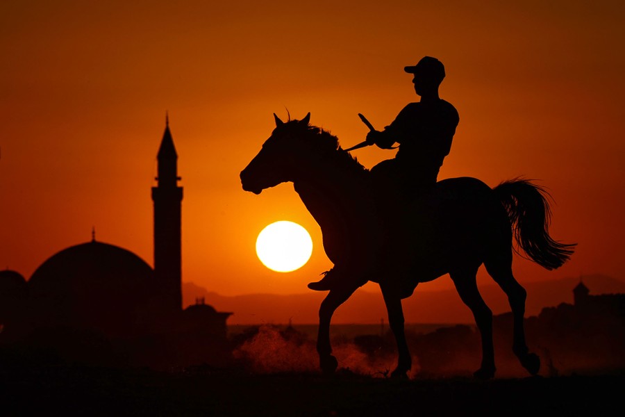 A silhouette of a mounted man, seen at sunset