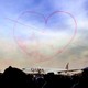 Pink smoke in the shape of a heart above an airplane