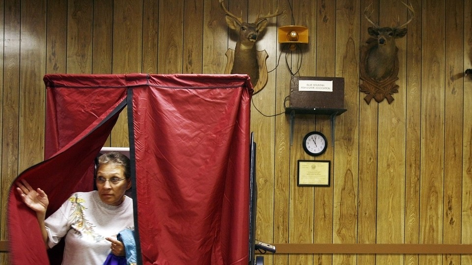 A woman leaves a voting booth with a blue curtain, set in front of hunting trophies, in Danielsville, Pennsylvania