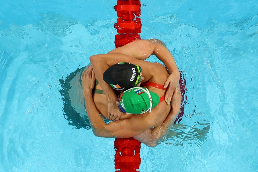 Two swimmers embrace in a pool, photographed from above, after an Olympic race.