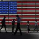 Pedestrians walk past an American flag in part of Times Square in New York City. 
