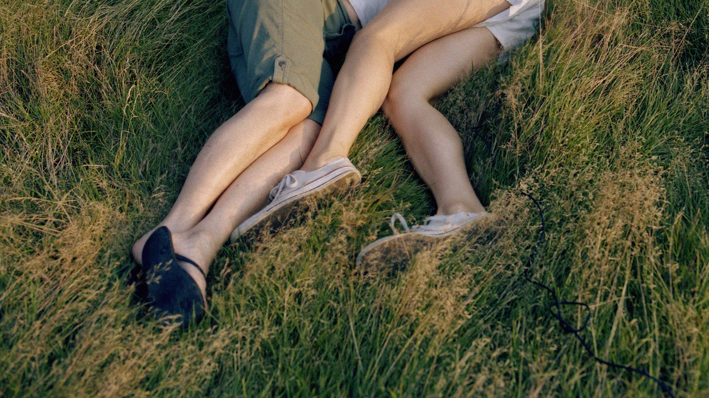 A photograph of two sets of legs in the grass, knees facing one another