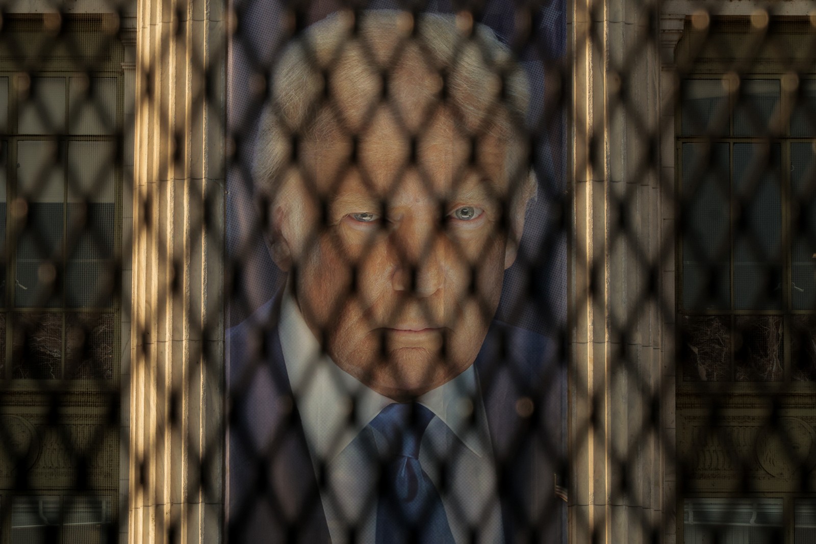 A banner with the image of President Donald Trump, seen through a section of security fencing
