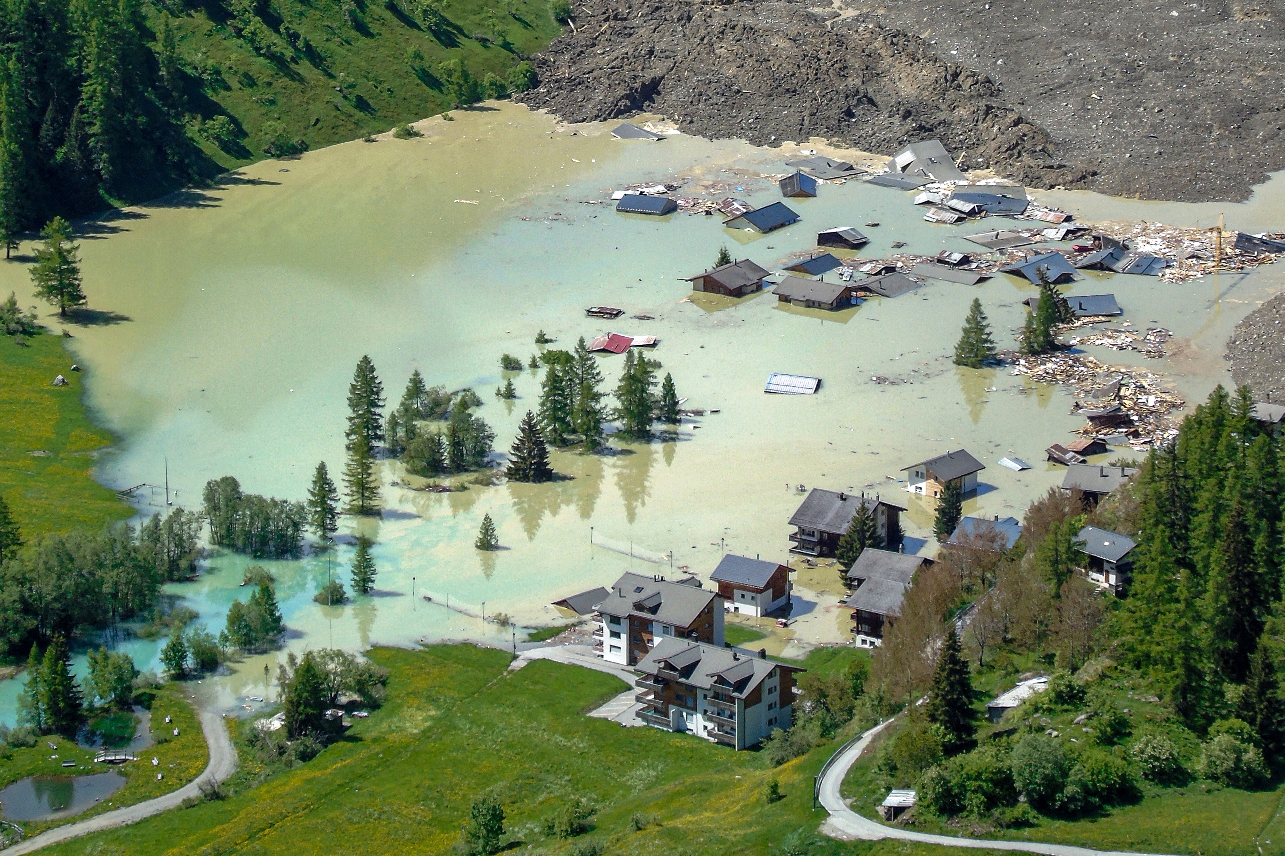 Part of a landslide-damaged mountain village, being slowly flooded by rising water.