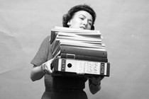 A black-and-white photo of tired woman holding a bunch of files