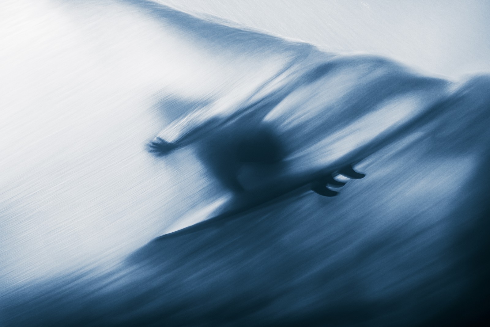 A motion-blurred image of a surfer riding a wave, seen from below