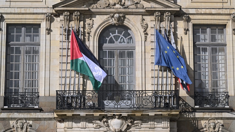 Photo of a Palestine flag and European Union flag waving on the face of a building