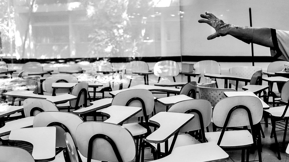 A hand wearing a cleaning glove gestures in a classroom filled with empty tablet-arm chairs.