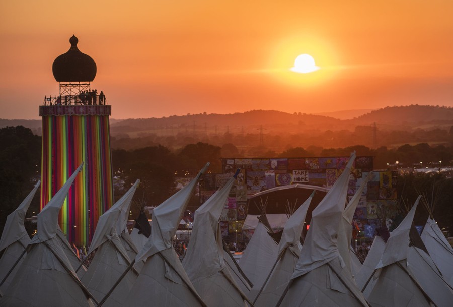 A sunset view of tents, a tower, and a stage