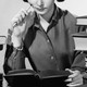 A woman reading a book surrounded by piles of books