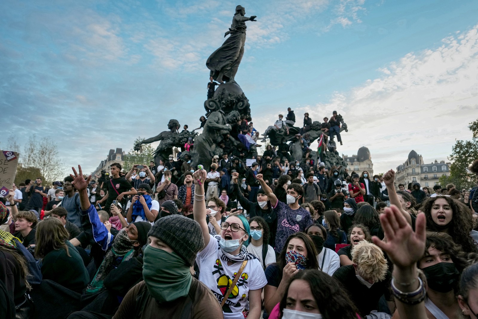 People gather on and around a large statue in Paris during a student protest.