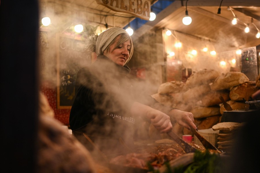 A person prepares food on a grill in a market stall.