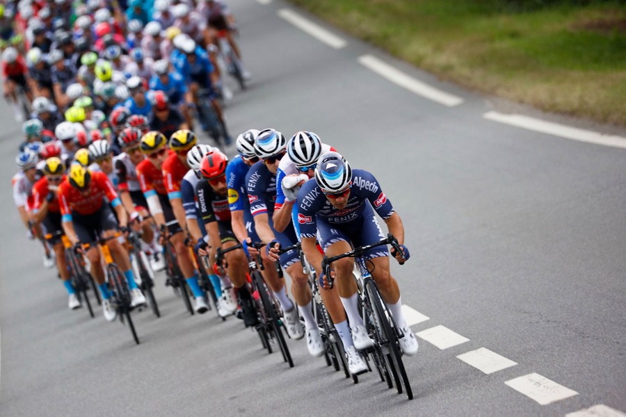 Dozens of cyclists ride down a road together.