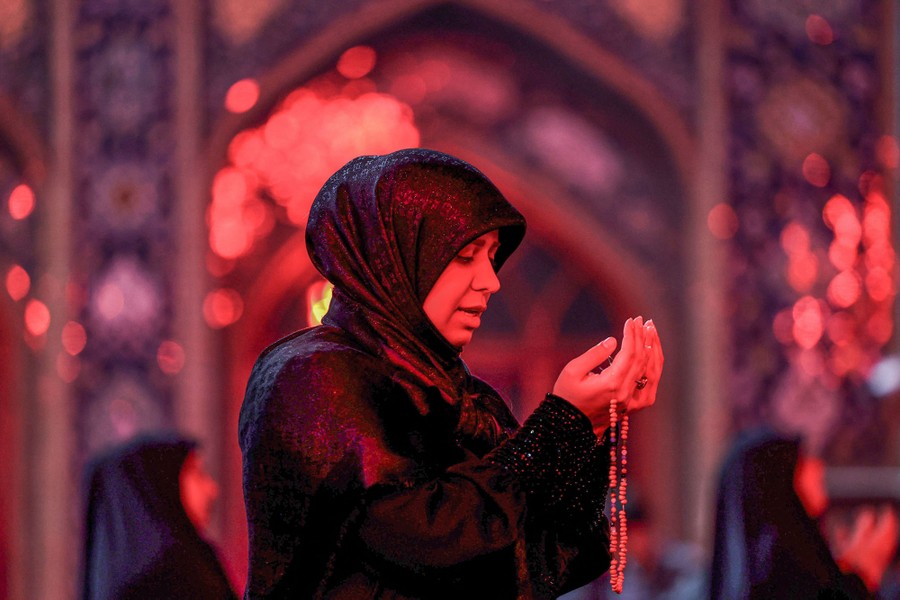 Μια γυναίκα προσεύχεται έξω από ένα τζαμί.