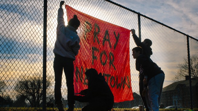 People pin a banner to a fence in Newtown.