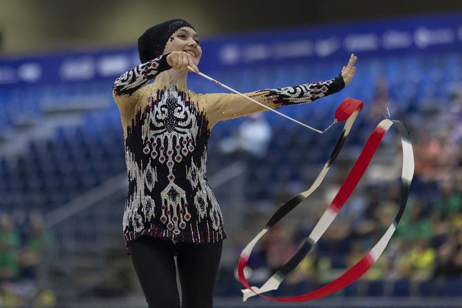 A gymnast performs a routine in a stadium.